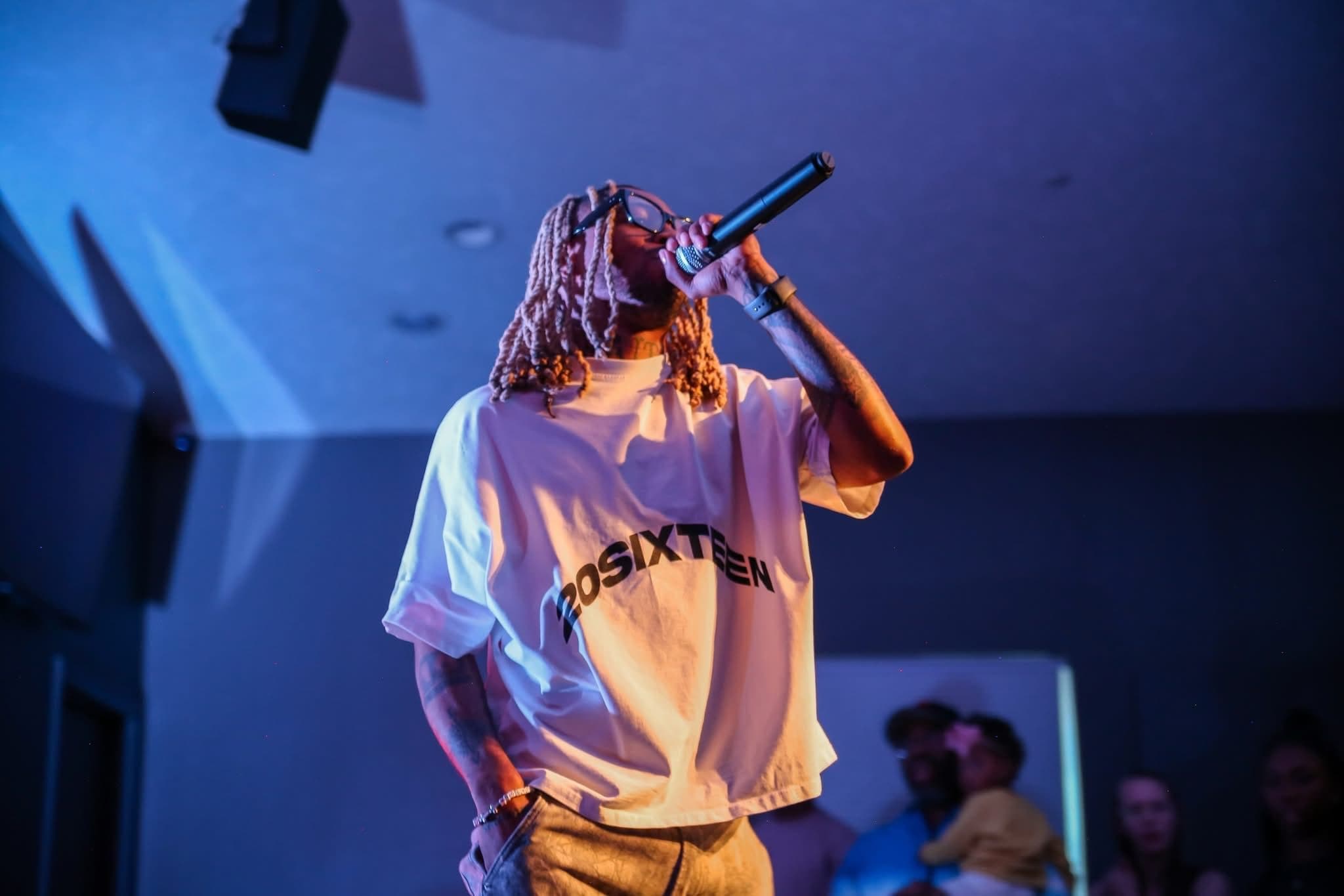 An artist performs under blue stage lights at Summer Glory.