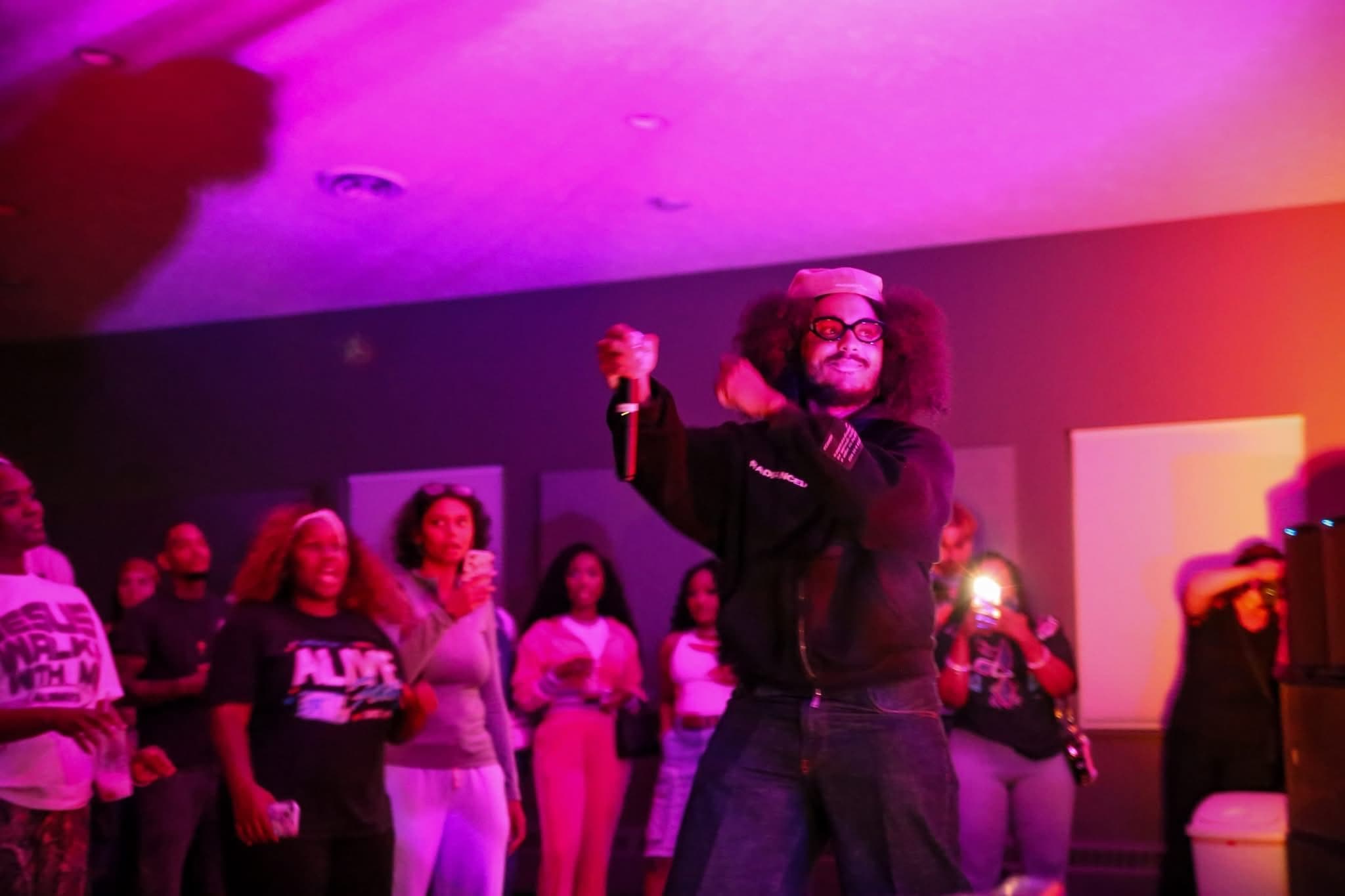 An artist performs right up against the crowd under pink stage lights at Summer Glory.