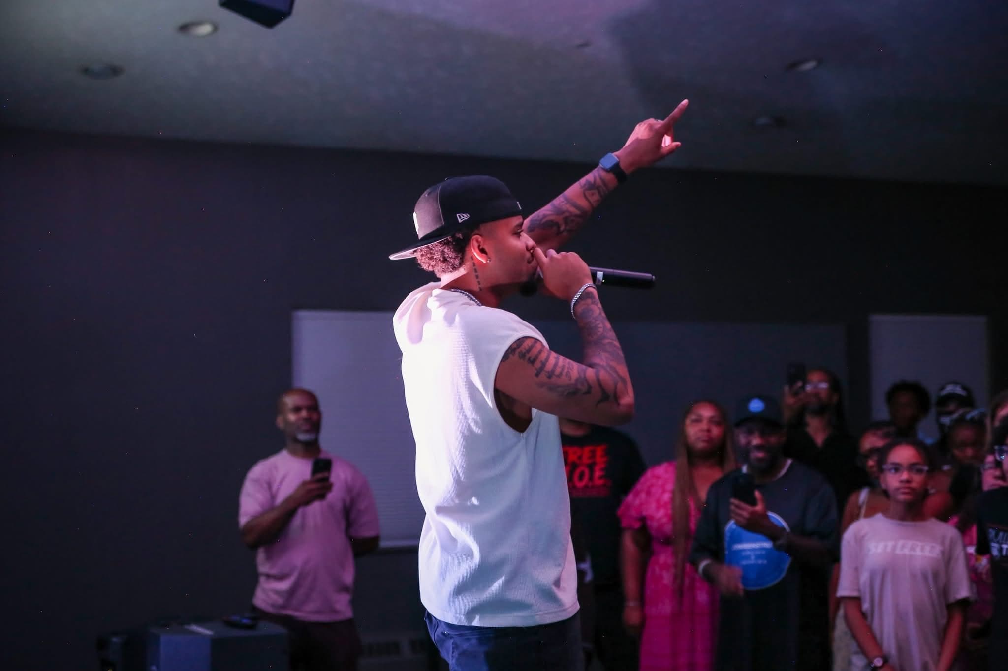 An artist points upward mid-performance as the crowd looks on at Summer Glory.